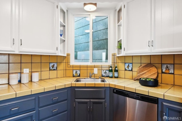 kitchen with blue cabinetry, decorative backsplash, stainless steel dishwasher, white cabinets, and a sink