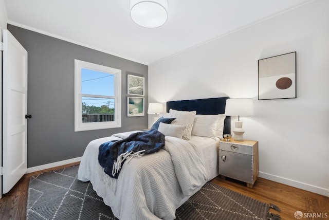 bedroom with baseboards, dark wood-type flooring, and ornamental molding