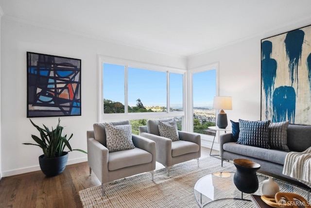 living area with a wealth of natural light, crown molding, baseboards, and wood finished floors