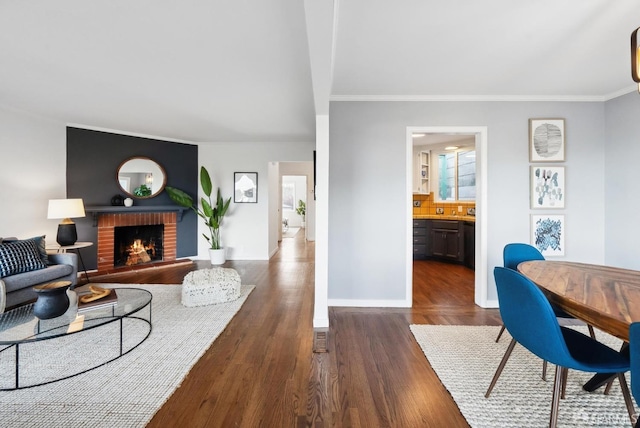 living room with a fireplace, crown molding, baseboards, and dark wood-style flooring