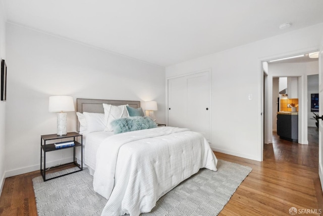 bedroom featuring wood finished floors, a closet, and baseboards