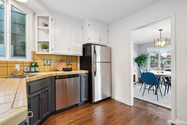 kitchen with white cabinetry, tile counters, appliances with stainless steel finishes, and ornamental molding