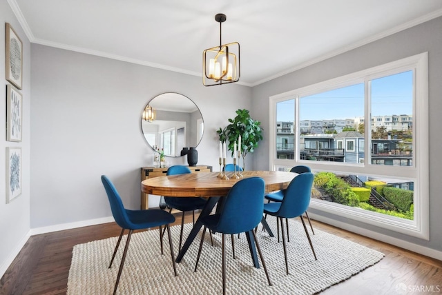 dining room with a notable chandelier, crown molding, baseboards, and wood finished floors