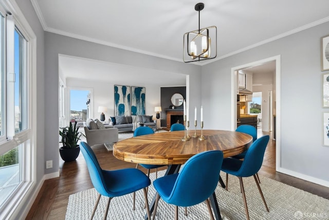 dining area with an inviting chandelier, ornamental molding, baseboards, and wood finished floors