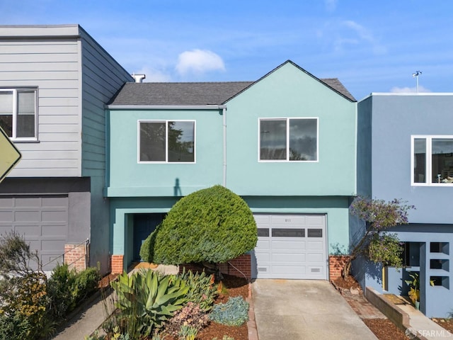 view of front of house featuring a garage, a shingled roof, concrete driveway, and stucco siding