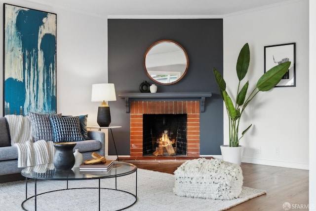 living room with a fireplace, crown molding, wood finished floors, and baseboards