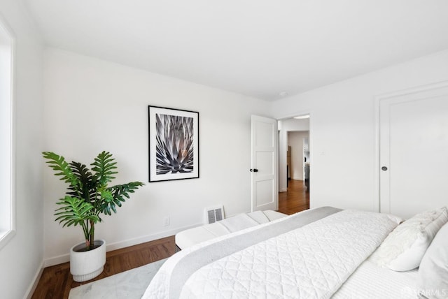 bedroom featuring wood finished floors, visible vents, and baseboards