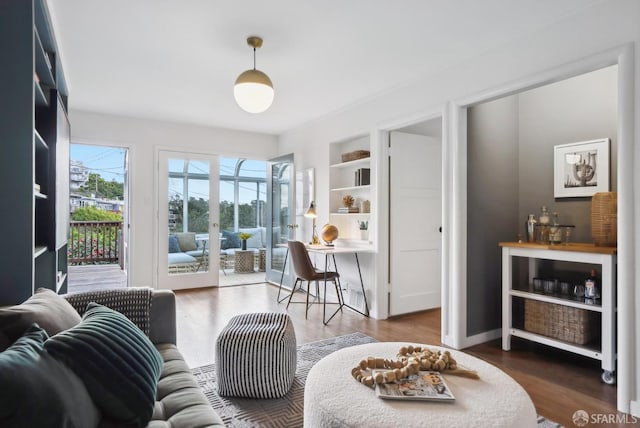 living room with built in features, baseboards, and wood finished floors