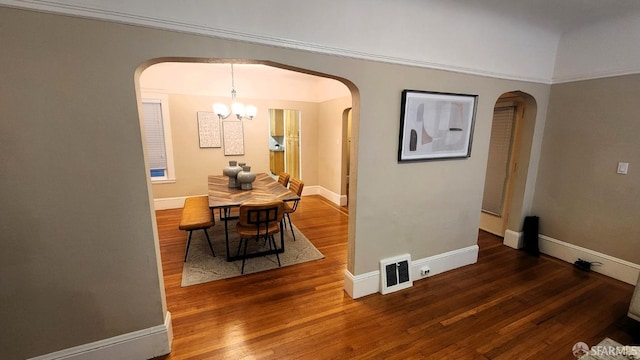 dining area with dark wood-type flooring and an inviting chandelier