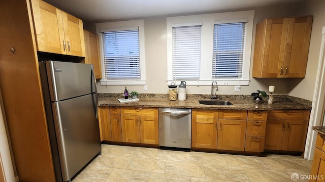 kitchen with stainless steel appliances, sink, and dark stone countertops