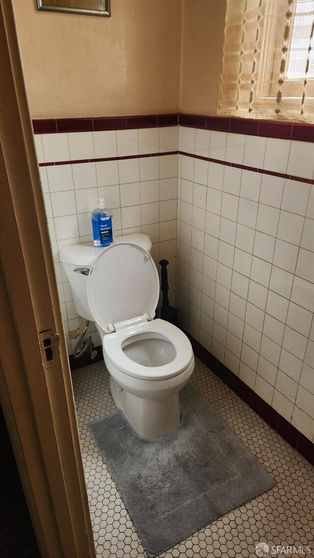 bathroom featuring tile patterned floors, toilet, and tile walls