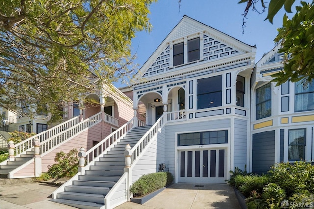 view of front facade featuring an attached garage, a porch, stairway, and concrete driveway