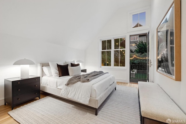 bedroom featuring access to outside, wood finished floors, and lofted ceiling