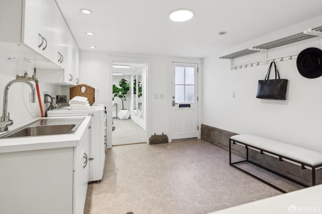 interior space with a sink, white cabinetry, washing machine and dryer, and light countertops