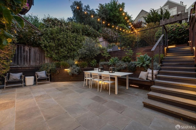 view of patio with fence, outdoor dining area, and stairs