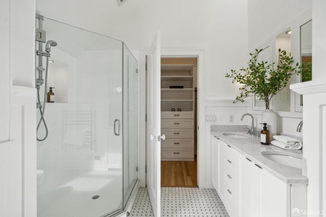 bathroom with double vanity, tile patterned floors, a spacious closet, a shower stall, and a sink