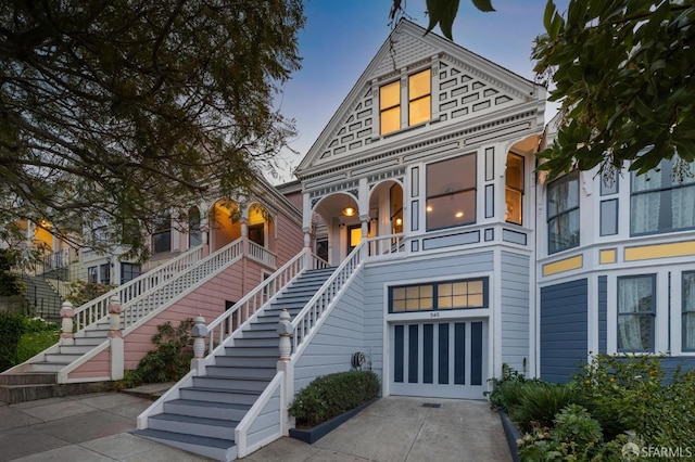 victorian home featuring stairs, an attached garage, and concrete driveway