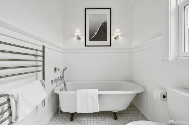 full bath with a freestanding tub, wainscoting, and toilet