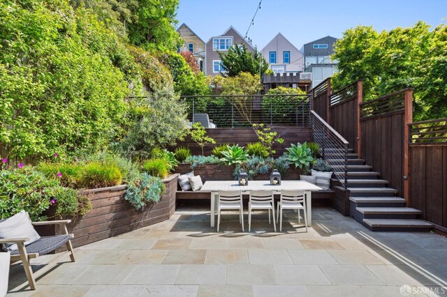 view of patio with stairs, fence, a residential view, and outdoor dining space