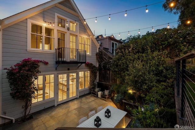 rear view of property with french doors, fence, a patio, and a balcony