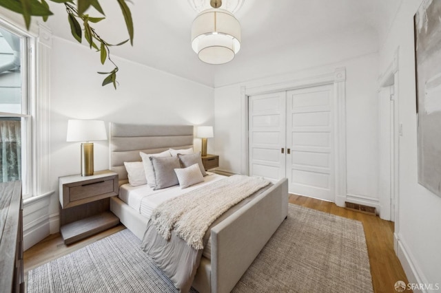 bedroom featuring baseboards, visible vents, wood finished floors, and a closet
