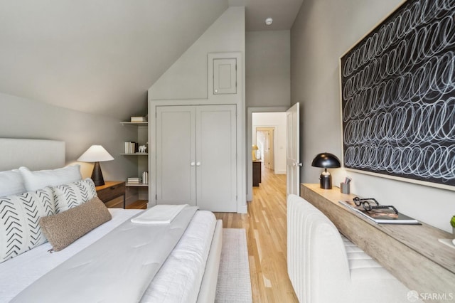 bedroom with light wood finished floors and lofted ceiling