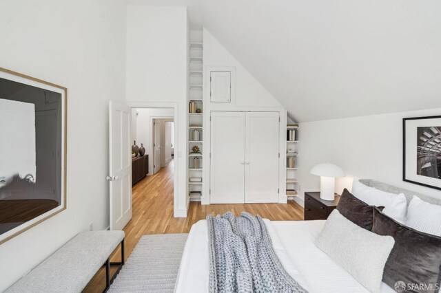 bedroom featuring a closet, light wood-type flooring, and lofted ceiling