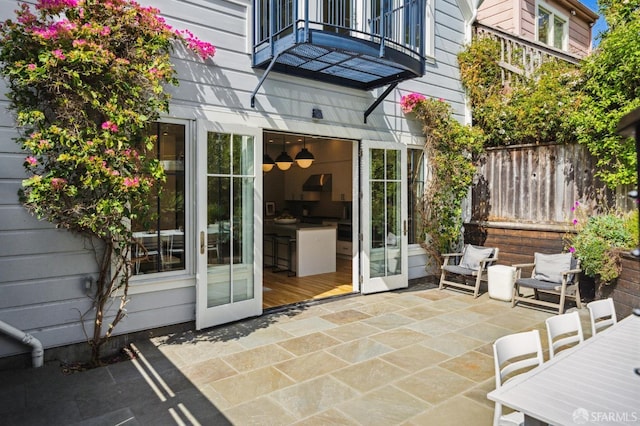 doorway to property with fence, a balcony, and a patio area