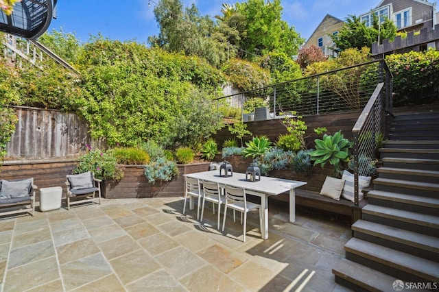 view of patio / terrace featuring a fenced backyard, stairway, and outdoor dining space