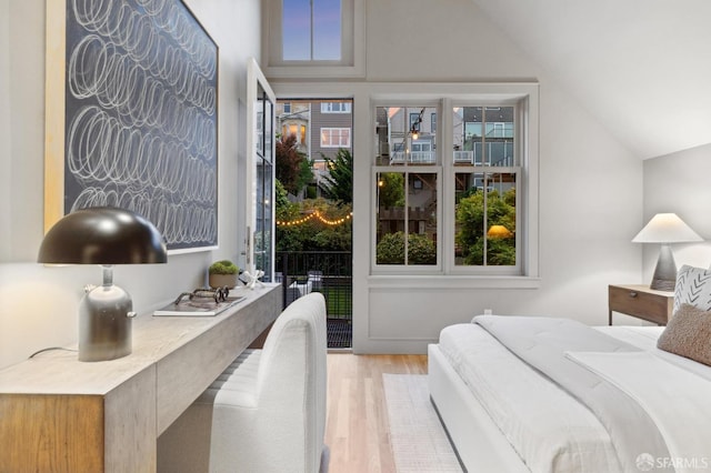 bedroom with multiple windows, access to exterior, wood finished floors, and lofted ceiling