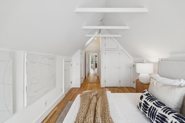 bedroom with vaulted ceiling and light wood-style flooring