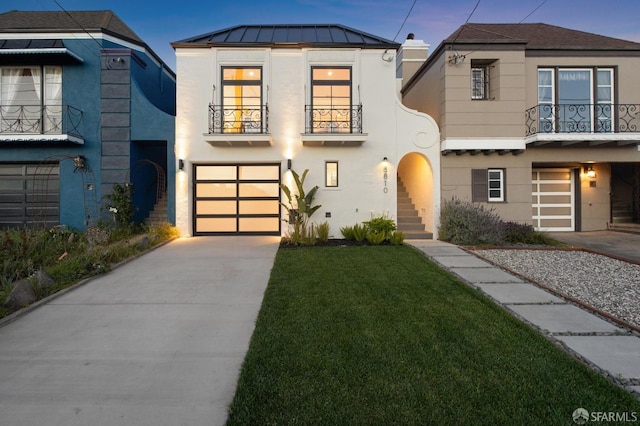 view of front facade with a balcony, a garage, and a yard