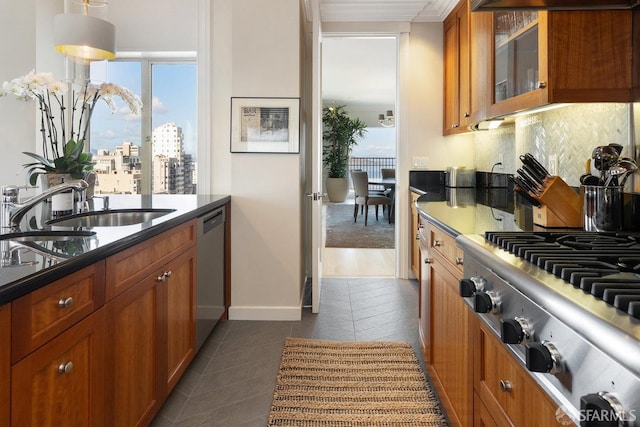 kitchen featuring a sink, brown cabinetry, stainless steel appliances, dark tile patterned flooring, and backsplash