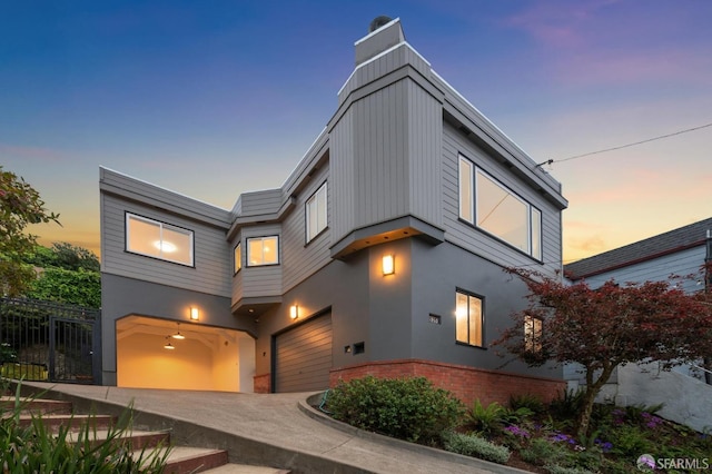 modern home featuring fence, an attached garage, a chimney, and stucco siding