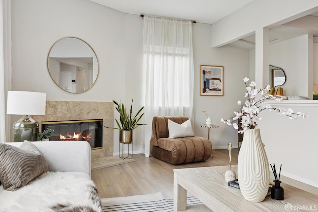 sitting room with a premium fireplace, baseboards, and wood finished floors