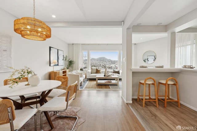 dining room with wood finished floors, baseboards, recessed lighting, a mountain view, and a notable chandelier