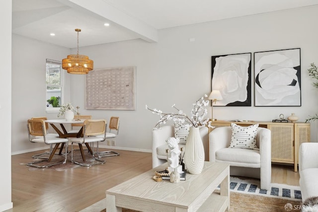 living area with baseboards, beamed ceiling, wood finished floors, and a notable chandelier