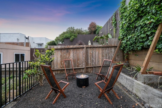 patio terrace at dusk with a fire pit and a fenced backyard