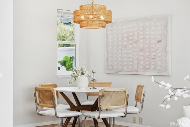 dining room with baseboards, wood finished floors, and a notable chandelier