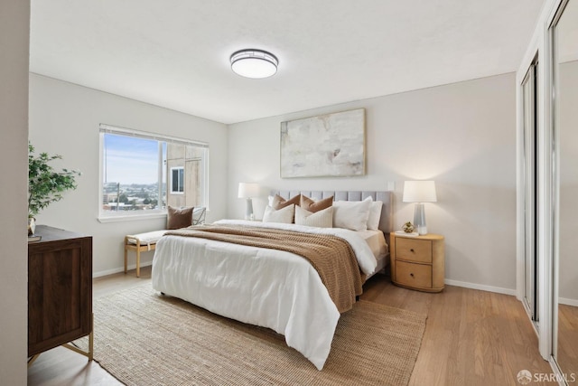 bedroom with baseboards, light wood-style flooring, and a closet
