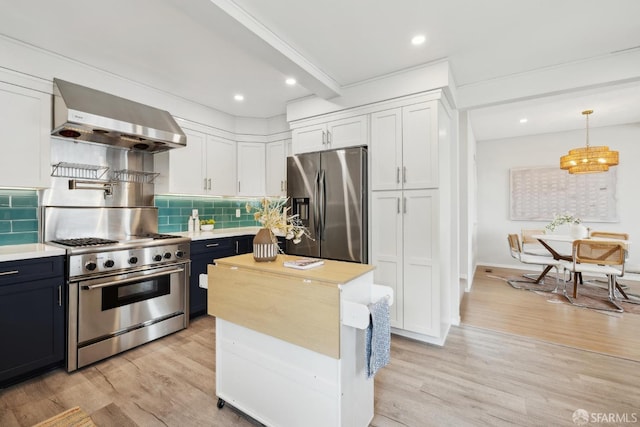 kitchen with white cabinets, light countertops, wall chimney exhaust hood, stainless steel appliances, and light wood-type flooring