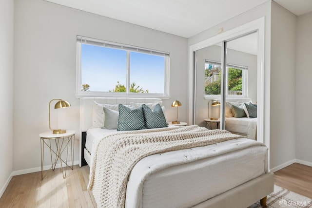 bedroom with baseboards, a closet, and light wood-style flooring