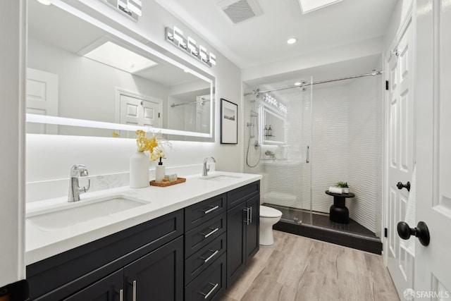 bathroom featuring visible vents, a shower stall, a sink, and wood finished floors