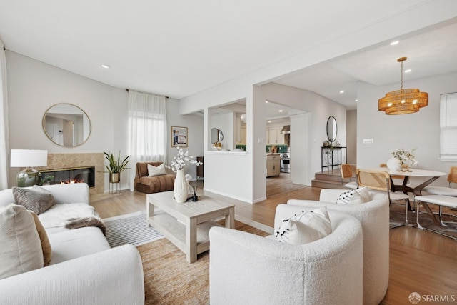 living room featuring recessed lighting, a glass covered fireplace, and light wood finished floors