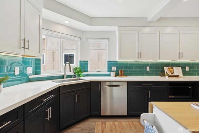 kitchen with a sink, light countertops, stainless steel dishwasher, and white cabinetry