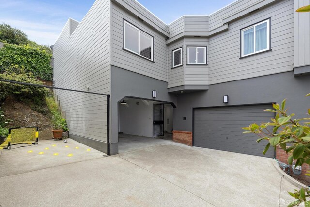 rear view of house featuring an attached garage, concrete driveway, and stucco siding