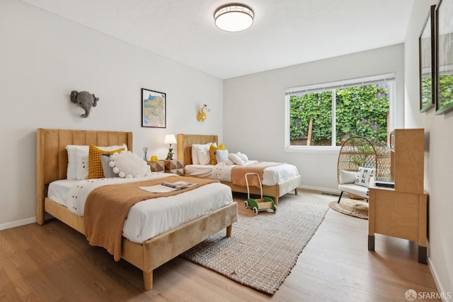bedroom featuring baseboards, wood finished floors, and visible vents