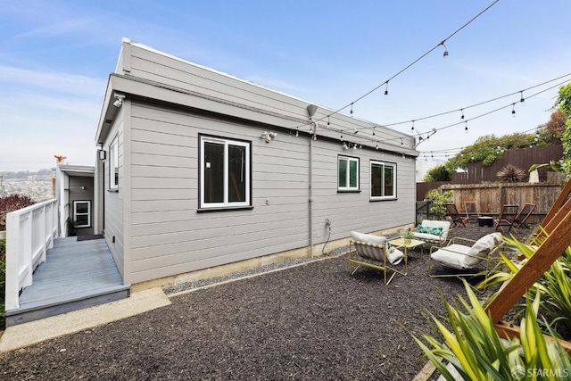 rear view of property with fence, a wooden deck, and outdoor lounge area