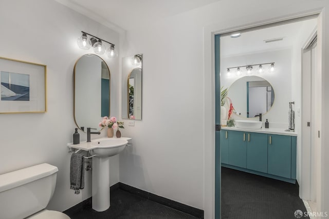 bathroom featuring toilet and dual sinks