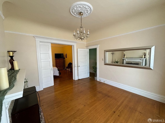 unfurnished dining area featuring baseboards, a notable chandelier, and dark wood-style flooring